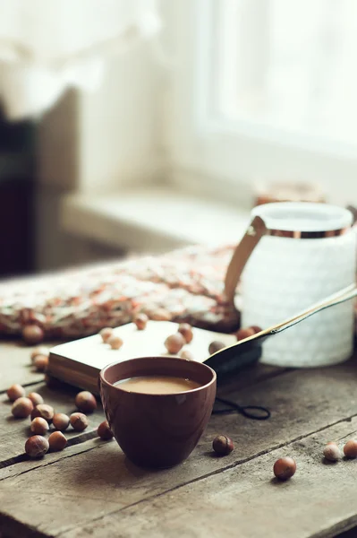 cozy morning at home, coffee and book with nuts on table, selective focus, warm toned