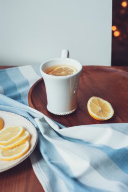 tea with lemon slices on wooden plate, vintage toned, cozy morning at home
