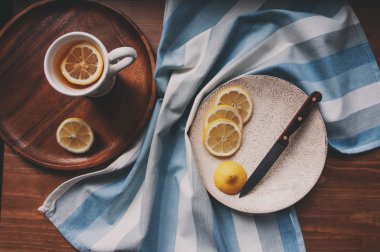 hot tea with lemon slices on wooden table, top view, cozy home setting