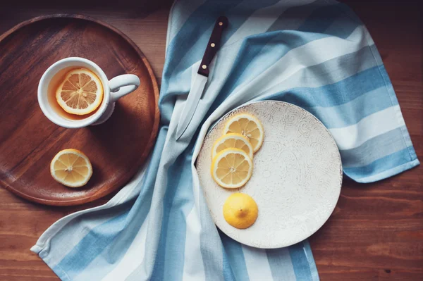 Hot tea with lemon slices on wooden table, top view, cozy home setting — Stock Photo, Image