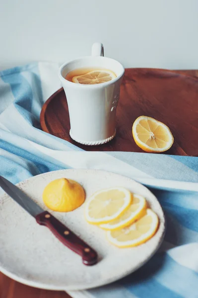 Tè con fette di limone su piatto di legno, vintage tonica, accogliente mattina a casa — Foto Stock