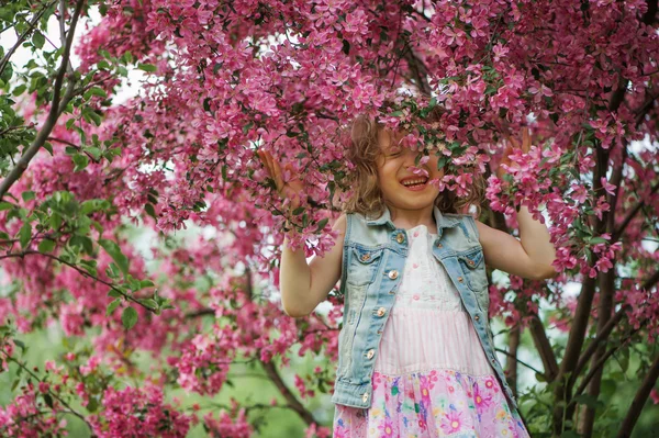 Niña feliz en vestido jugando cerca del árbol en flor en el jardín de primavera. Rural ambiente acogedor, actividades de temporada al aire libre . — Foto de Stock