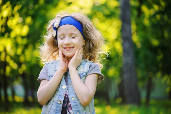 Niña feliz jugando en campo de primavera colorido. Dientes de león florecientes en el fondo, actividades de temporada al aire libre. Ambiente cálido acogedor . — Foto de Stock