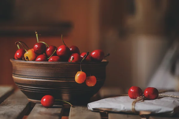 Ciliegie fresche su piatto con regalo avvolto su tavolo di legno. Vintage tonica, concetto di vita contadina. Concentrazione selettiva. Home crescita bacche estive — Foto Stock