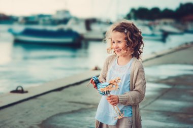 Deniz rahatlatıcı ve oyuncak kuş ile oynayan kız sevimli kıvırcık çocuk. Portoroz, Slovenya yaz tatile seyahat.