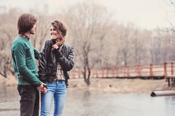 Feliz jovem casal amoroso andando no campo no início da primavera dia chuvoso . — Fotografia de Stock