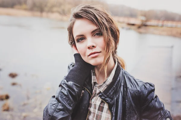 Outdoor portrait of adorable young woman in leather jacket and plaid skirt. Soft warm toned, cozy mood. — Stock Photo, Image