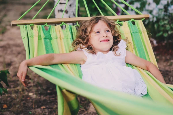 happy child girl relaxing in hammock on summer camp in forest. Outdoor seasonal activities for kids.