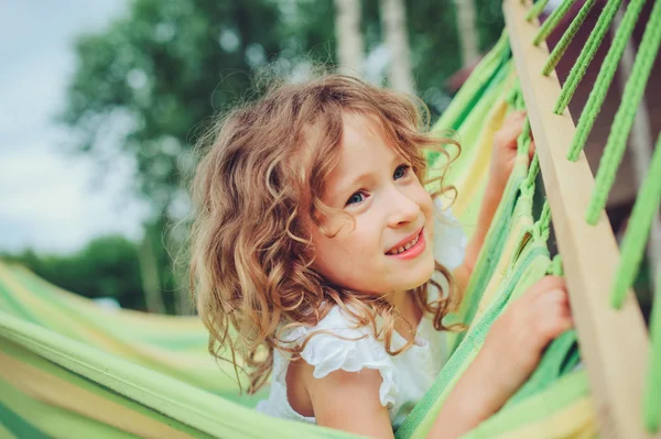 Niña feliz relajarse en hamaca en el campamento de verano en el bosque. Actividades de temporada al aire libre para niños . — Foto de Stock