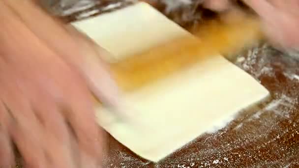 Руки человека, катящего тесто по столу — стоковое видео