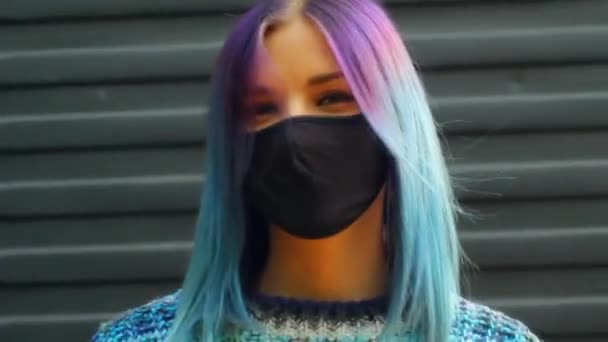 Jong meisje met blauw haar in beschermende zwarte masker kijken direct naar de camera. Urban fashion outfit, kapsel. COVID-19 — Stockvideo