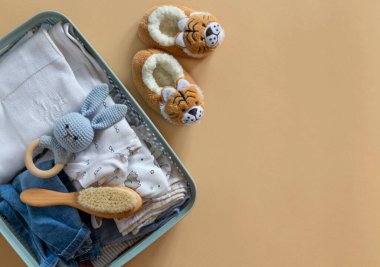 Bebek Unisex tarafsız giysileri ve bej arka planda bağış aksesuarları olan bağış kutusu. Düz yat ve boşluğu kopyala