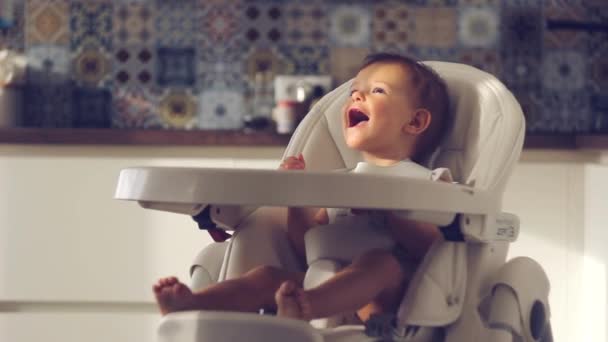 Mães Mão dando comida para sua filha bebê feliz na cadeira alta na cozinha em casa — Vídeo de Stock