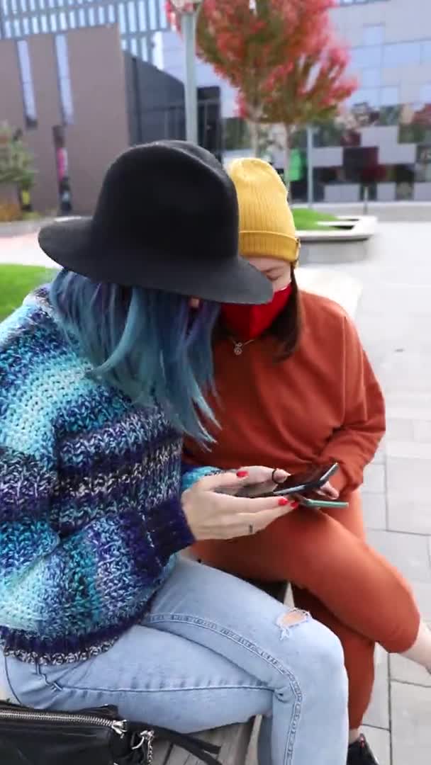 2 női barátok védő orvosi arc maszk okostelefonok kívül. Függőleges videó — Stock videók