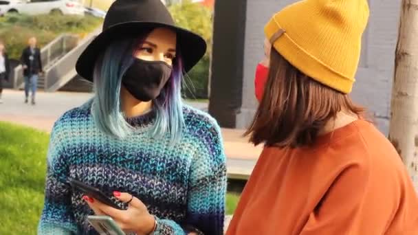 2 밖에 스마트폰을 가지고 의료용 마스크를 쓰고 있는 여성 친구들 — 비디오