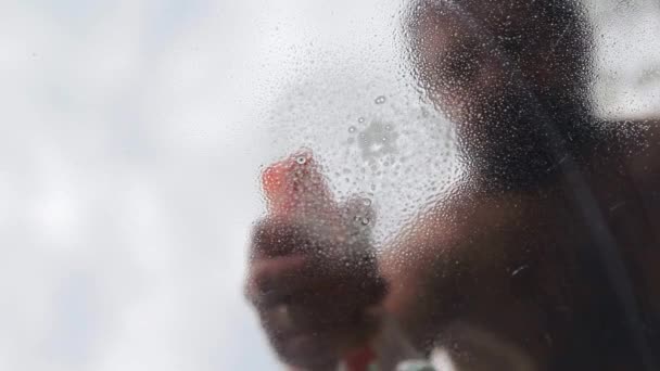 Um homem pulveriza detergente no vidro. — Vídeo de Stock