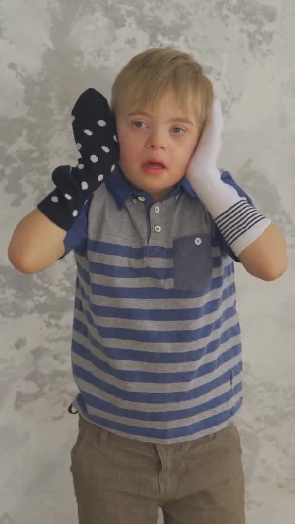 Down sendromlu, elinde çoraplarla saklambaç oynayan tatlı bir çocuk. Dikey biçim — Stok video