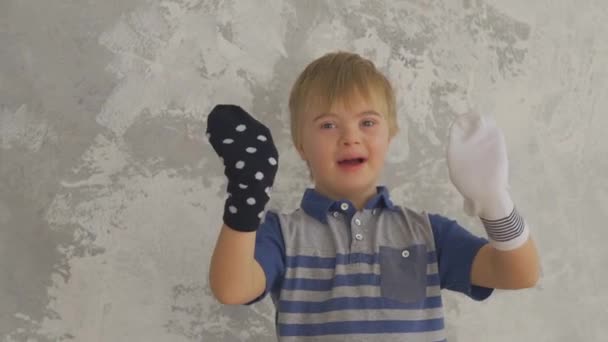 Μικρό αγόρι με σύνδρομο Down διασκεδάστε με κάλτσες στα χέρια του — Αρχείο Βίντεο