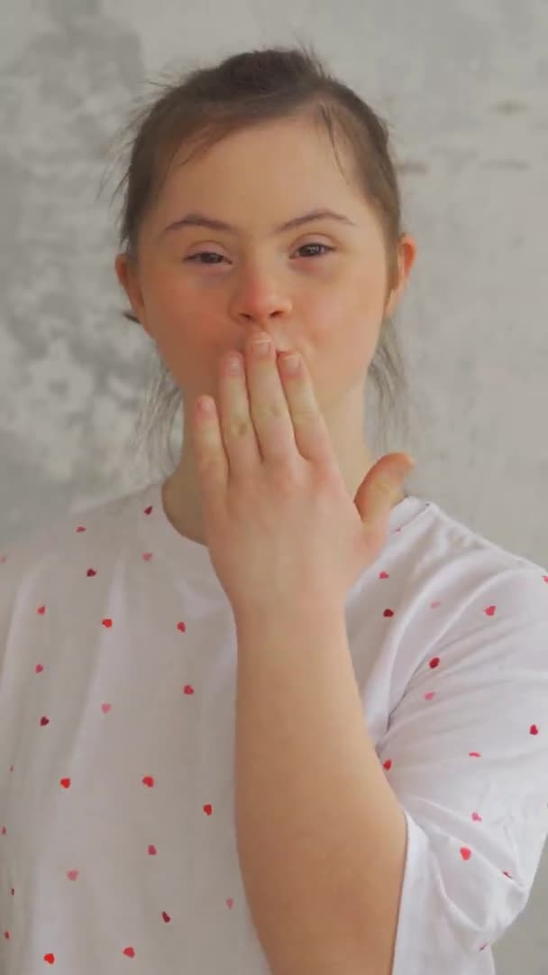Detailní záběr dospívající dívky s Downovým syndromem posílá polibek. Svislý formát — Stock video