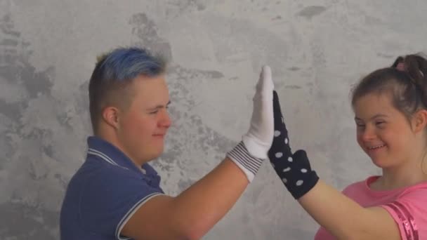 Fröhliches Teenager-Paar mit Down-Syndrom amüsiert sich mit Socken an den Händen — Stockvideo