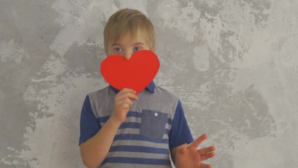 Menino doce com Síndrome de Down, brincando com o coração de papel — Vídeo de Stock