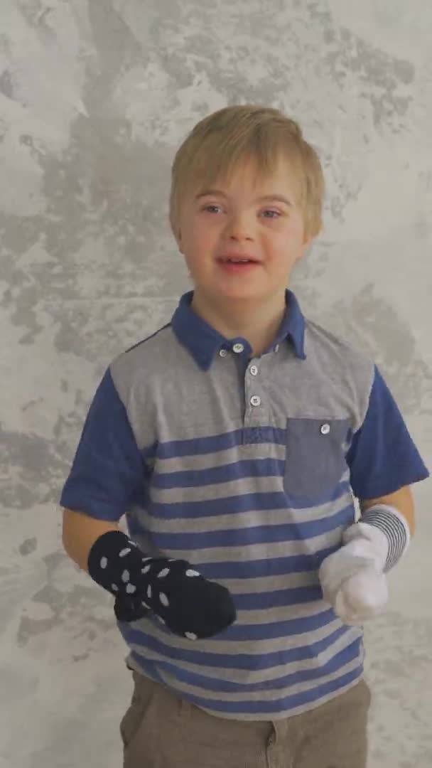 다운 증후군이 있는 귀여운 소년이 양말을 신고 재미를 보고 있습니다. 수직 형태 — 비디오