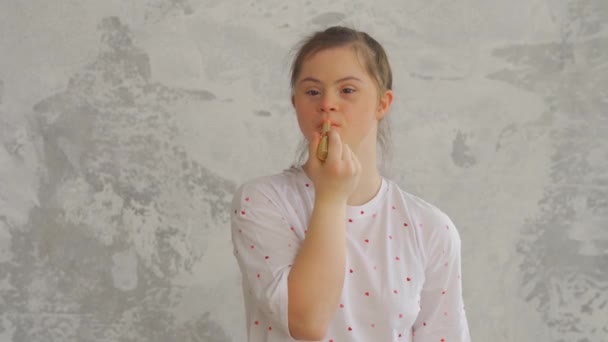 Attraktiv glad tonåring flicka med Down Syndrom målar läppar med läppstift — Stockvideo