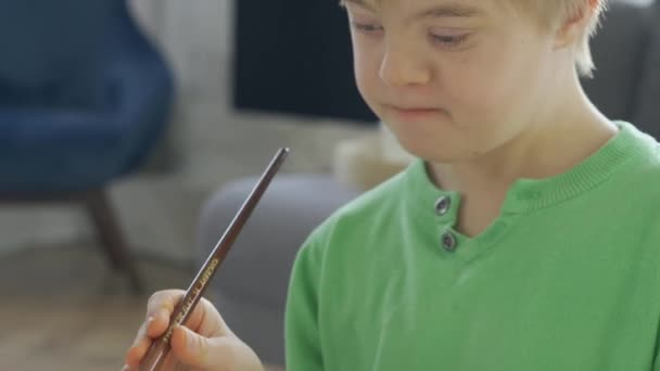 Primer plano del niño con síndrome de Down dibujo en casa — Vídeos de Stock
