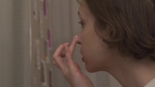 Close-up of teen girl applying moisturizing hydrating cream looking in mirror — Stock Video