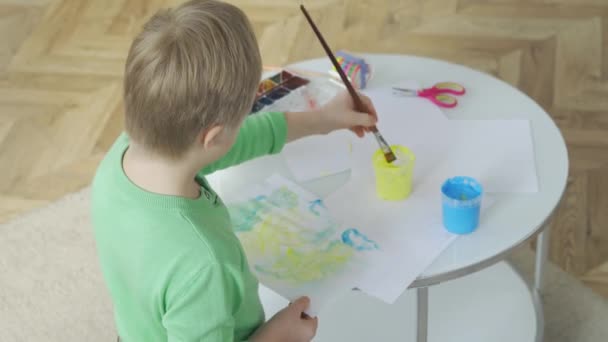 Vista de trás de um menino com síndrome de Down desenho em casa — Vídeo de Stock