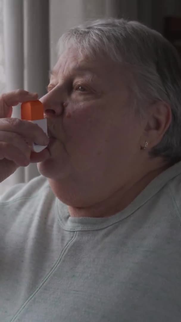 Une femme âgée utilise un inhalateur à la maison. Format vertical — Video