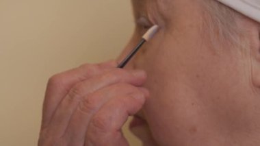 Göz farı süren komik, yaşlı bir kadının yakın çekimi.