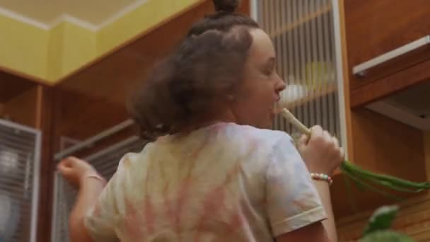 Chica adolescente preparando ensalada y cantando con cebolletas. — Vídeos de Stock