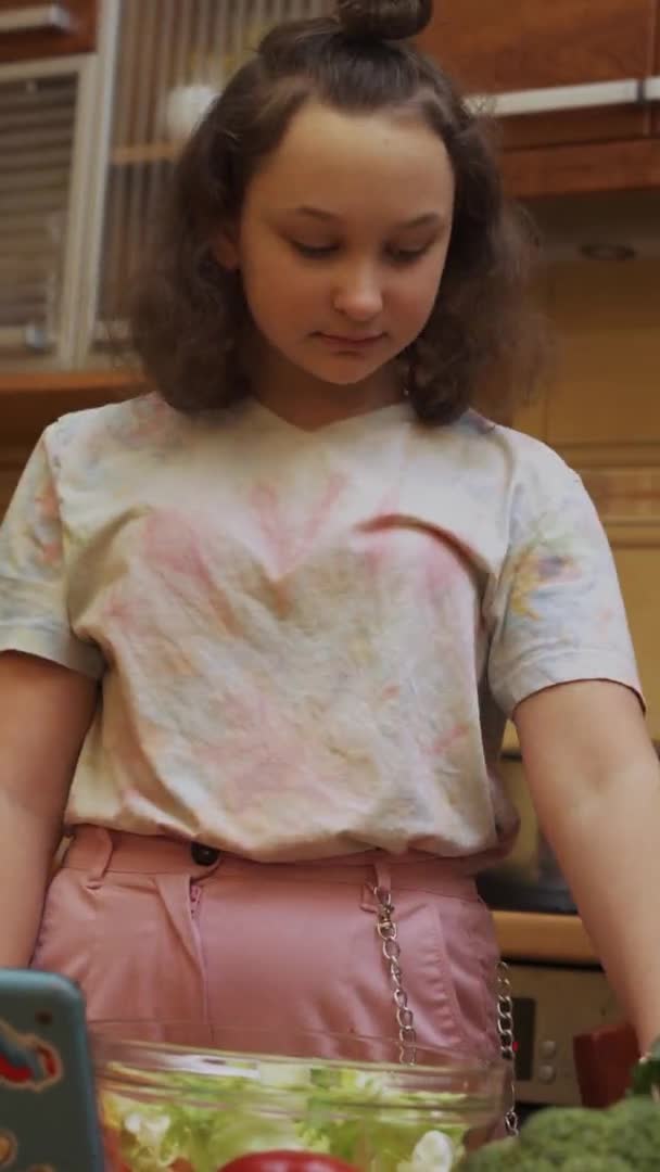 Menina adolescente preparando salada com tablet digital. Formato vertical — Vídeo de Stock