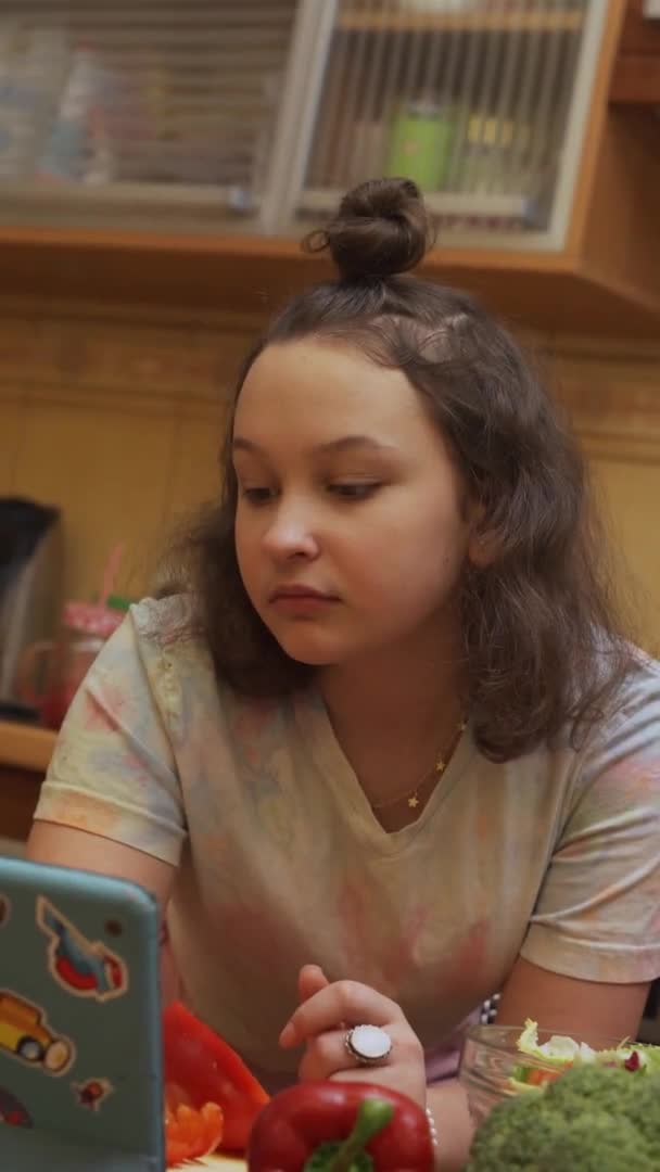 Adolescente recherche la recette sur une tablette numérique dans la cuisine. Format vertical — Video