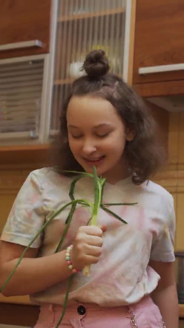 Egy tinédzser lány salátát készít és Scallionsszal énekel. Függőleges formátum — Stock videók