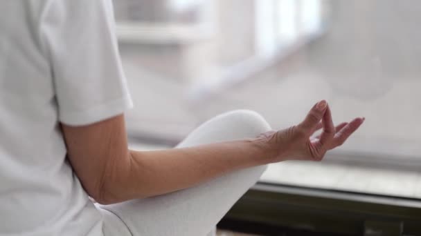 Close-up de Senior mulher praticando ioga em posição de lótus em casa. — Vídeo de Stock