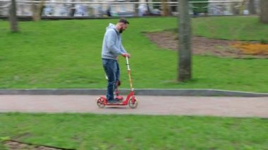 Mutlu baba ve küçük kız parkta scooterla geziyorlar. Aile ve babalık kavramı