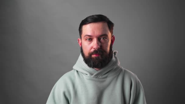 Retrato de hombre barbudo moviendo sus cejas sobre fondo gris — Vídeo de stock