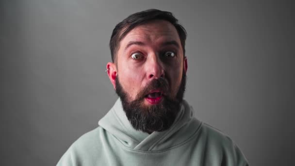 Portret van een grappige man met een baard die verrast naar de camera kijkt - geschoten in slow motion — Stockvideo