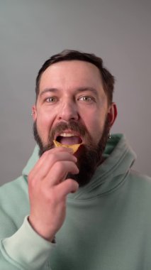 Sakallı adam ağır çekimde tortilla cipsi yiyor. Dikey görünüm