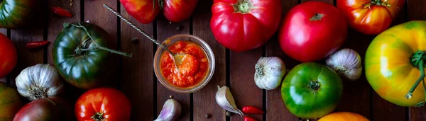 Hausgemachte Adjika-Tomatensauce in Schüssel mit frischen Zutaten - Tomaten, Chilischote, Knoblauch auf Holztisch. Flache Lage — Stockfoto