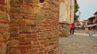 NESEBAR, BULGARIA - 2021 HAZİRAN: Akşam vakti eski kasabanın sokaklarında martıları besleyen adam