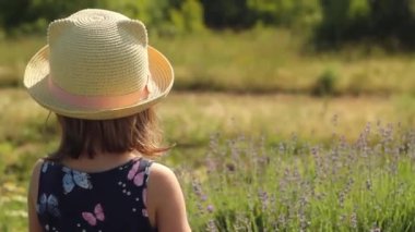 Şapkalı küçük bir kız bir demet lavanta topluyor..