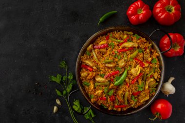 İspanyol paella pilavı ve arka planda tavuk.