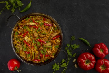 İspanyol paella pilavı ve arka planda tavuk.