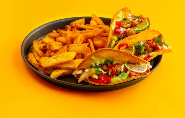 Mexikanischer Taco mit französischen Kartoffeln in schwarzer Pastete auf gelbem Hintergrund — Stockfoto