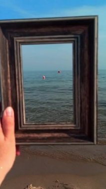 Sahilde el ele tutuşan fotoğraf çerçevesi. Dikey video biçimi