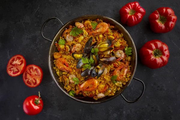 Traditional spanish seafood paella with tomatoes on a black background — Stock Photo, Image