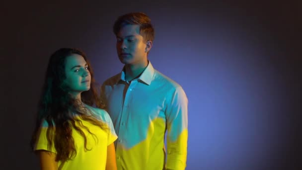 Két tizenéves pózol a stúdióban a projektor Tükröződik a kék és sárga ukrán zászló — Stock videók